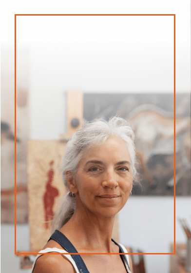 Older woman with white hare standing in front of several paintings