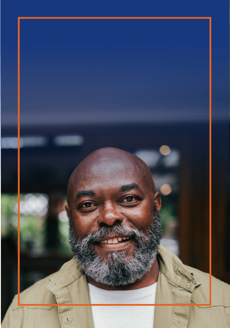 Older man smiling while standing in front of a store