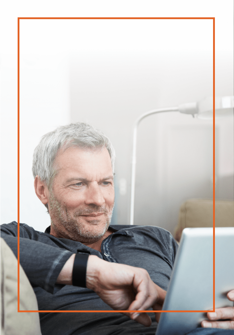 Older man sitting on a couch with a tablet in hand