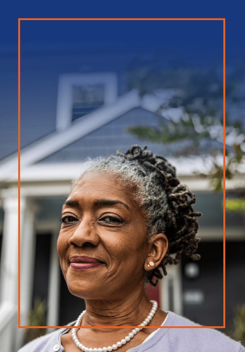 Older woman smiling in front of her home