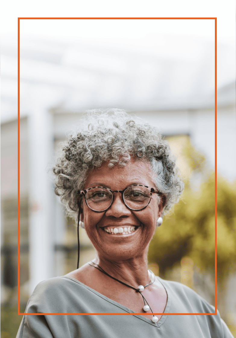 Older woman smiling as she stands in front of a building
