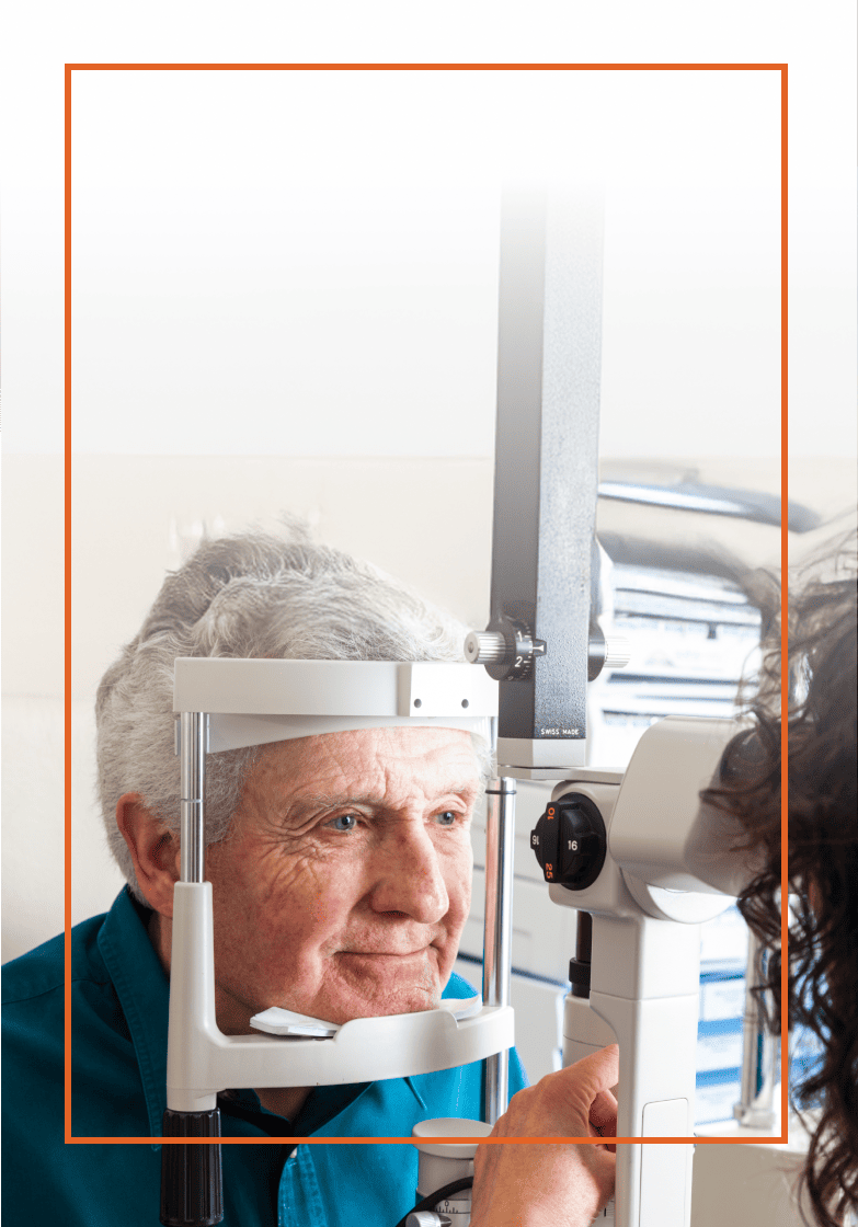 Elderly man getting an eye exam, his head is placed in some examination equipment