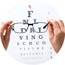 Close up of a pair of glasses being held in front of an eye exam chart