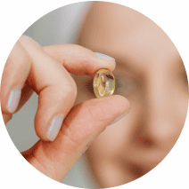 Close up of a woman holding an eye vitamin pill
