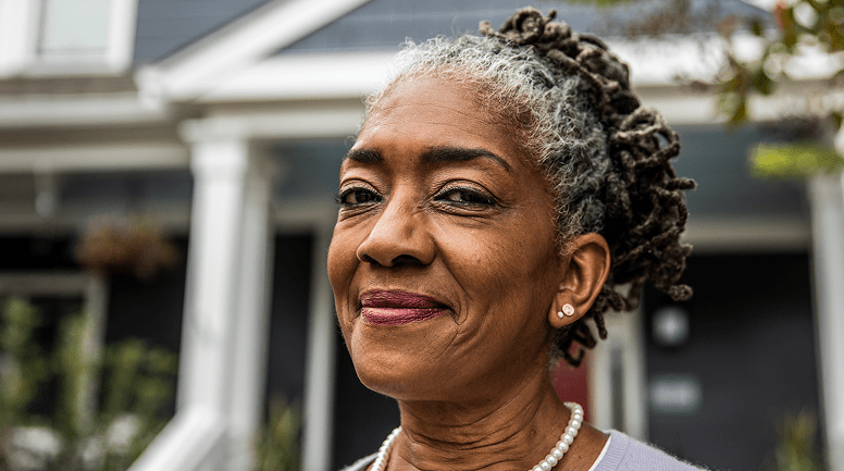Older woman smiling while standing outside her home