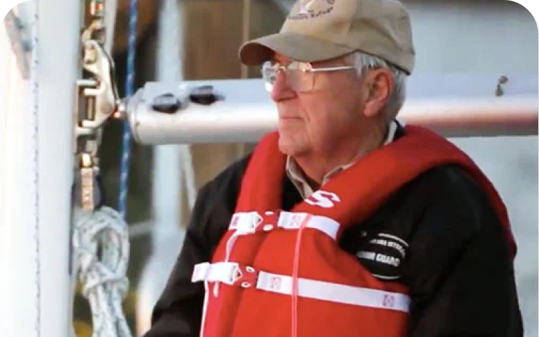 Elderly man wearing glasses and a life vest on a boat