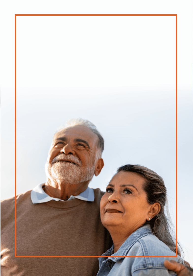 Older man and woman hold each other as they look off into the distance