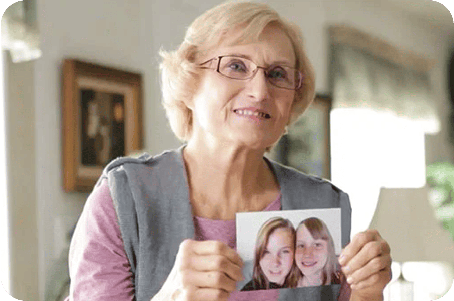 Older woman holding up a photo of two young women