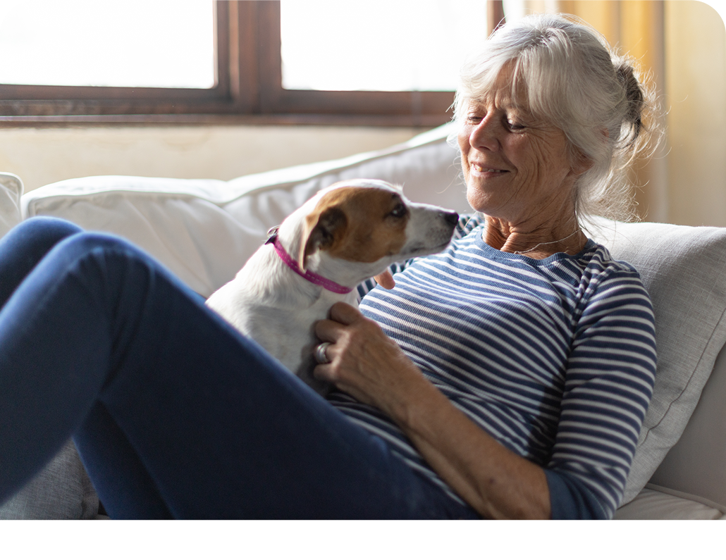 Elderly woman laying on a couch with a dog in her lap