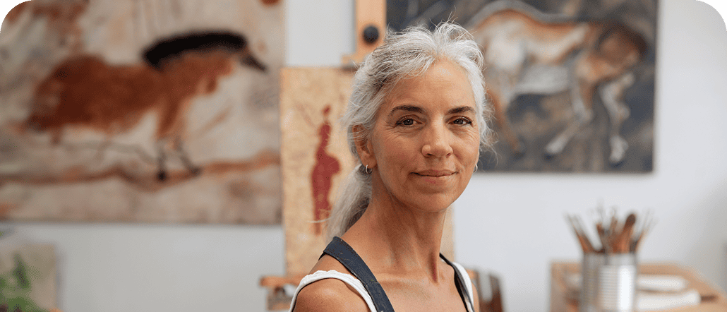 Older woman standing in front of several works of art