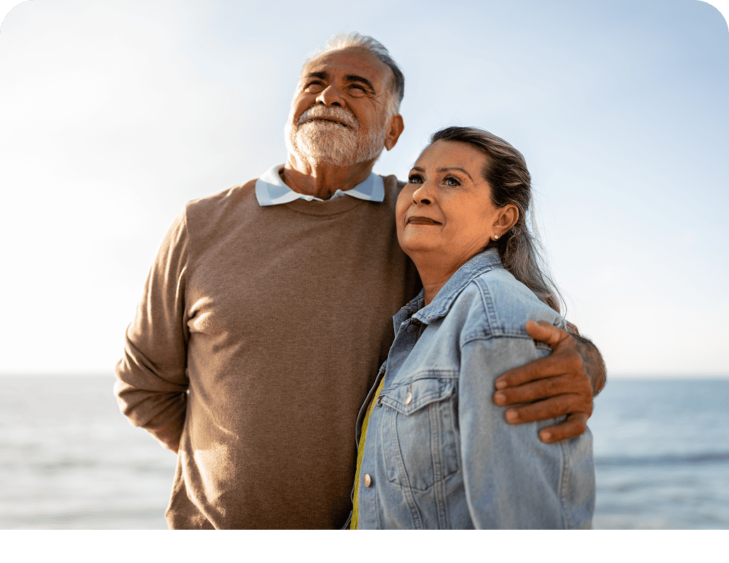 Older man and woman standing in front of the ocean